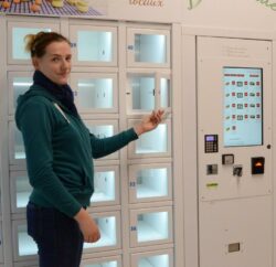 Marie, gérante du Panier Thunois, pose devant on distributeur automatique lors de l'installation