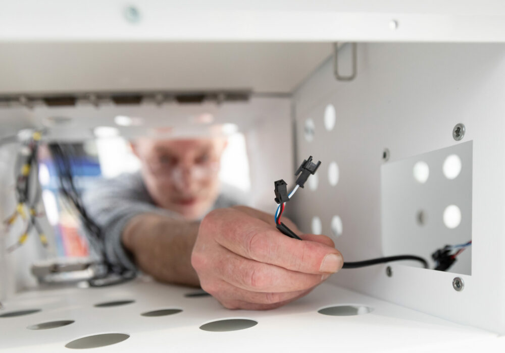 Technicien Le Casier Français en train faire les branchements électriques du distributeur automatique.