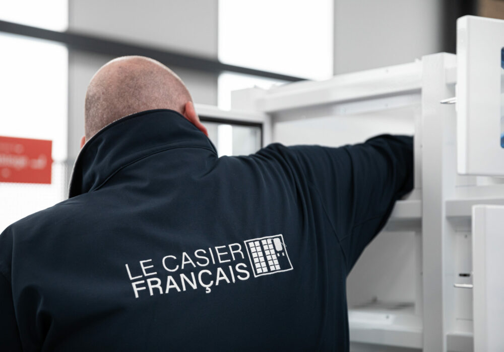 Zoom sur le logo de l'entreprise Le Casier Français sur la veste d'un technicien en train d'opérer les branchements dans un distributeur automatique